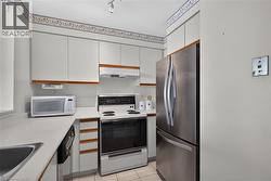 Compact kitchen featuring light-toned cabinetry with wood trim accents - 