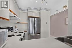 Kitchen featuring white cabinetry with wood trim, stainless steel French door refrigerator, white electric range, and double basin stainless steel sink - 