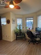 Bay window area featuring multiple windows, wood-finish flooring, a ceiling fan with integrated lighting, and neutral wall tones - 