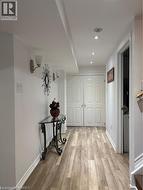 Hallway featuring wood-finish flooring, recessed lighting, and wall sconces - 
