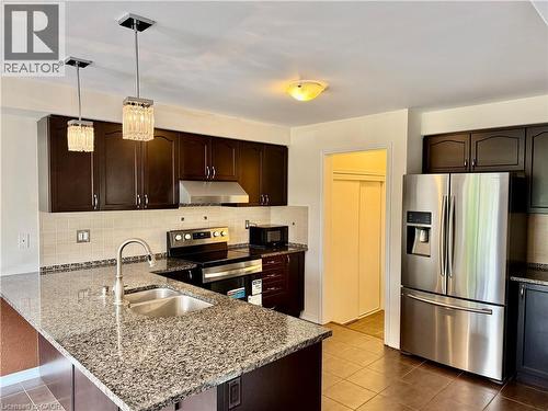 Kitchen featuring dark wood-finish cabinetry, granite-finish countertops, stainless steel appliances, and tile flooring - 386 Apple Hill Crescent, Kitchener, ON 