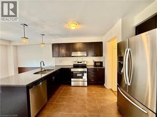 Contemporary kitchen featuring dark wood cabinetry, stainless steel appliances, granite countertops, and tile flooring - 386 Apple Hill Crescent, Kitchener, ON 