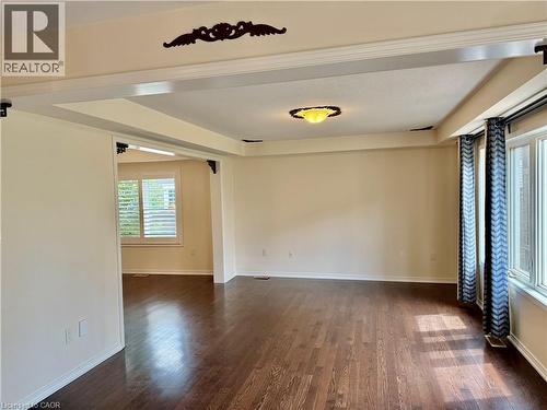 Spacious room featuring rich wood-finish flooring, an ornate ceiling light fixture, and a decorative ceiling medallion - 386 Apple Hill Crescent, Kitchener, ON 