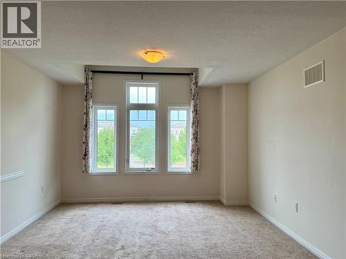 Room featuring a triple window assembly with transom, recessed ceiling detail, and neutral carpeting - 386 Apple Hill Crescent, Kitchener, ON 