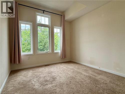 Room featuring a triple window arrangement with transom detail, neutral-toned walls, and plush carpeting - 386 Apple Hill Crescent, Kitchener, ON 