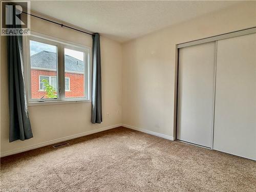 Carpeted room featuring a double window, baseboard trim, and a sliding door closet - 386 Apple Hill Crescent, Kitchener, ON 