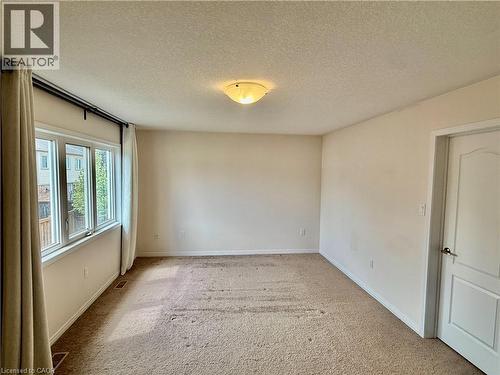 Expansive room featuring neutral wall paint, a multi-pane window with white trim, and a flush-mount ceiling light fixture - 386 Apple Hill Crescent, Kitchener, ON 