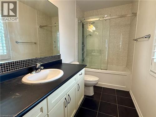 Bathroom featuring a vanity with a white basin and dark countertop, white shaker-style cabinetry, and a full-width mirror - 386 Apple Hill Crescent, Kitchener, ON 