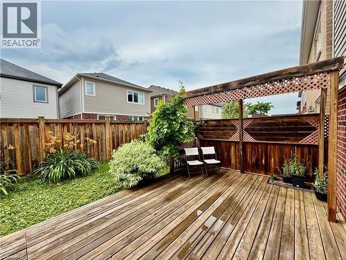 Expansive wood-finish deck with an integrated pergola featuring lattice accents, complemented by a privacy fence and garden beds with established plantings - 386 Apple Hill Crescent, Kitchener, ON 