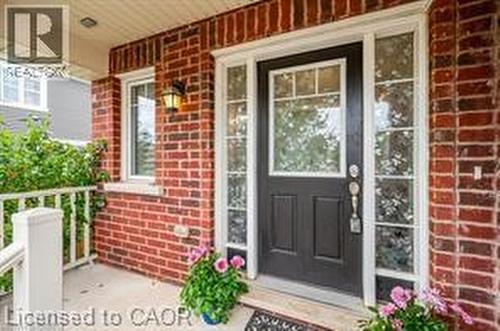 Brick exterior with white trim, featuring a dark entry door with upper window panes and sidelights - 386 Apple Hill Crescent, Kitchener, ON 