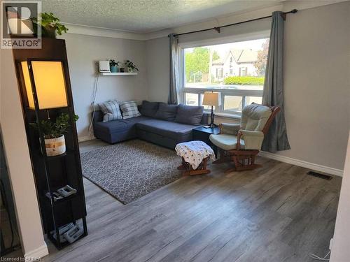 Bright living area featuring wood-finish flooring, a large picture window, and crown molding - 86 North Park Street, Brantford, ON 