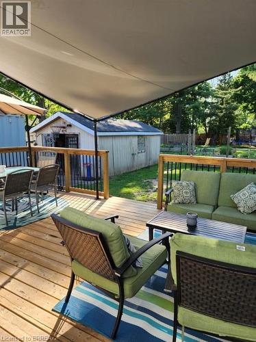 Expansive wooden deck featuring a shade sail, black railing, and a storage shed in the background - 86 North Park Street, Brantford, ON 