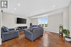 Spacious living area featuring rich wood-finish flooring, recessed lighting, and a large window providing expansive outdoor scenery - 