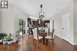 Open-concept kitchen and dining area featuring wood-finish flooring, recessed lighting, and a contemporary chandelier - 