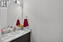 Vanity featuring a white oval undermount sink, a chrome single-handle faucet, and a stone-finish countertop with integrated backsplash - 