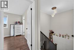 Stairwell featuring a dark wood newel post and balusters, a contemporary chandelier, and light gray wall paint - 