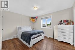 Bedroom featuring wood-finish flooring, a double-paned window, neutral wall paint, and a flush-mount ceiling light fixture - 