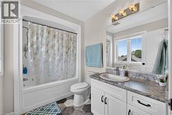 Bathroom featuring a white vanity with dark hardware, granite-look countertop, and an undermount sink - 