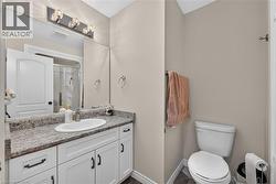 Vanity featuring an integrated oval sink, stone-finish countertop, and white shaker-style cabinetry with matte black hardware - 