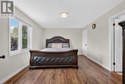 Spacious room featuring wood-finish flooring, light neutral wall tones, and white trim - 