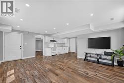 Open-concept living area featuring wood-finish flooring, recessed lighting, and a neutral wall color - 