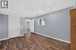 Spacious room featuring wood-finish flooring, light blue walls, and white trim - 