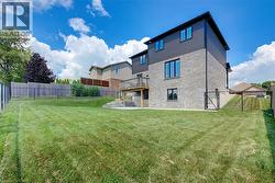 Expansive backyard featuring a manicured lawn, a multi-level wood deck, a concrete patio, and a privacy fence - 