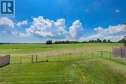 Expansive backyard featuring manicured lawn and partial chain-link fence - 