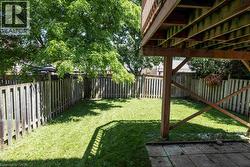Expansive backyard featuring a manicured lawn, established privacy fencing, and mature trees providing natural shade - 