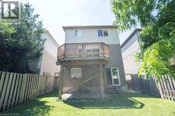 Rear exterior featuring a raised wood deck, a patio area with pavers, and a green lawn - 