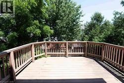 Expansive wood deck featuring a natural wood finish, full perimeter railing, and surrounding mature trees - 
