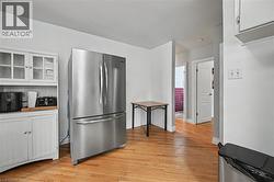 Kitchen area featuring hardwood flooring, a stainless steel French door refrigerator, and a white hutch with glass-front upper cabinets - 