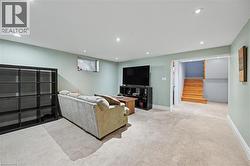 Recessed lighting illuminates this carpeted lower-level room, featuring light green walls and white trim - 