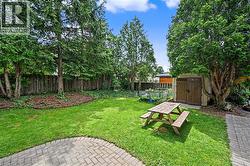 Expansive backyard featuring a lush lawn, mature trees, and a paved patio area - 