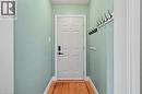 Entryway featuring a paneled door with modern hardware, wood-finish flooring, light green wall finishes, and white trim - 56 Everton Place, Hamilton, ON 