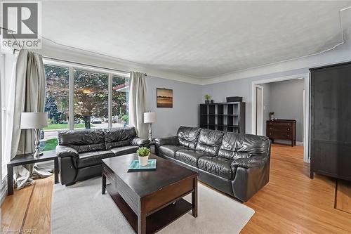 Spacious living area featuring large picture windows, wood-finish flooring, light blue wall paint, and a classic white ceiling - 56 Everton Place, Hamilton, ON 