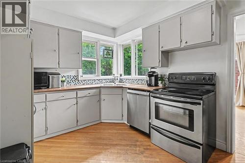 Kitchen featuring light-toned cabinetry, wood-finish countertops, and a mosaic tile backsplash - 56 Everton Place, Hamilton, ON 