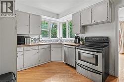 Kitchen featuring light-toned cabinetry, wood-finish countertops, and a mosaic tile backsplash - 