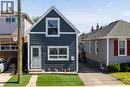 Front exterior featuring dark blue siding with white trim, a gabled roofline, and a prominent upper-level window - 23 Britannia Avenue, Hamilton, ON 