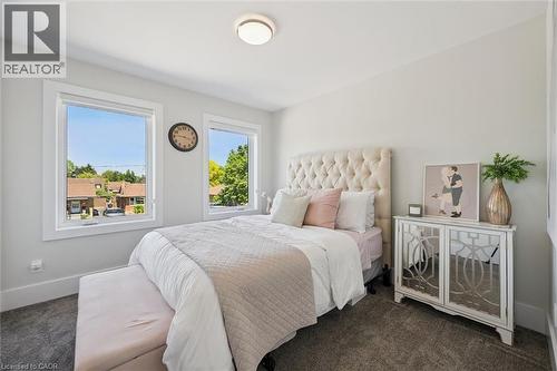 Light-filled room featuring wall-to-wall carpeting, two large windows with white trim, a flush-mount ceiling light, and neutral wall paint - 63 Plymouth Road, Kitchener, ON 