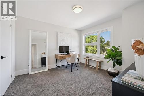 Carpeted room featuring a large window, white trim, and a flush-mount ceiling light - 63 Plymouth Road, Kitchener, ON 