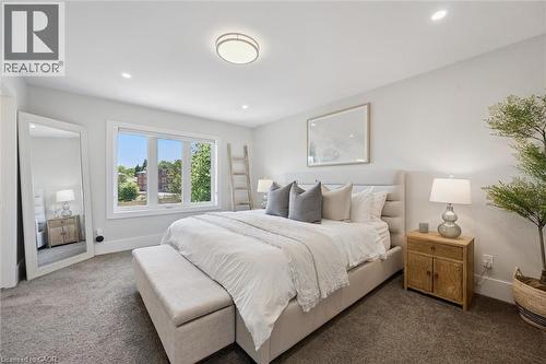 Bright bedroom featuring a large multi-pane window, recessed lighting, a ceiling-mounted light fixture, and plush carpeting - 63 Plymouth Road, Kitchener, ON 