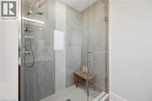 Glass-enclosed shower featuring large format wall tiles, a mosaic tile accent stripe, and a dual shower head system - 63 Plymouth Road, Kitchener, ON 