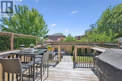Multi-level wooden deck featuring a glass-top bar table, built-in counter space, and a lower patio area - 63 Plymouth Road, Kitchener, ON 