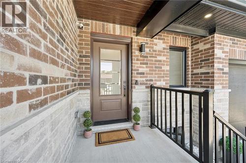 Entryway featuring a solid wood front door with a glass insert, complemented by brick and stone veneer siding - 63 Plymouth Road, Kitchener, ON 