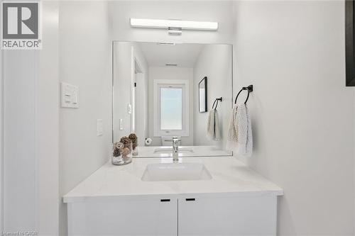 Modern vanity featuring a white rectangular undermount sink, a white stone-finish countertop, and white cabinetry with integrated pulls - 63 Plymouth Road, Kitchener, ON 
