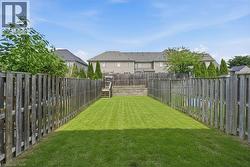 Spacious backyard featuring a wood privacy fence, expansive green lawn, and a tiered wood deck with steps - 