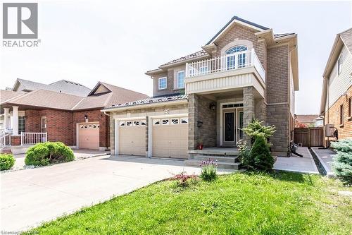 Brick and stone exterior featuring a covered entryway, a second-story balcony with decorative railing, and an arched window - 252 Thorner Drive Unit# Basement, Hamilton, ON 