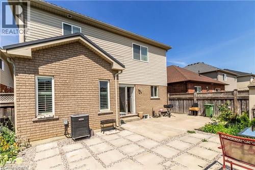 Rear facade featuring brick and siding construction, ground-level patio with stone pavers, and partial privacy fencing - 252 Thorner Drive Unit# Basement, Hamilton, ON 