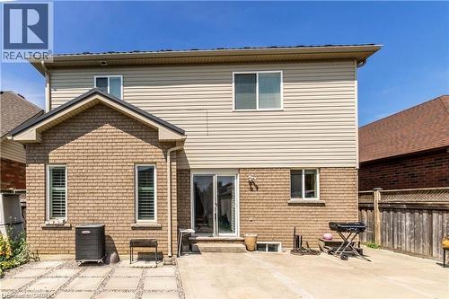 Rear exterior featuring brick and vinyl siding, multiple windows, a sliding glass door, and a paved patio area - 252 Thorner Drive Unit# Basement, Hamilton, ON 